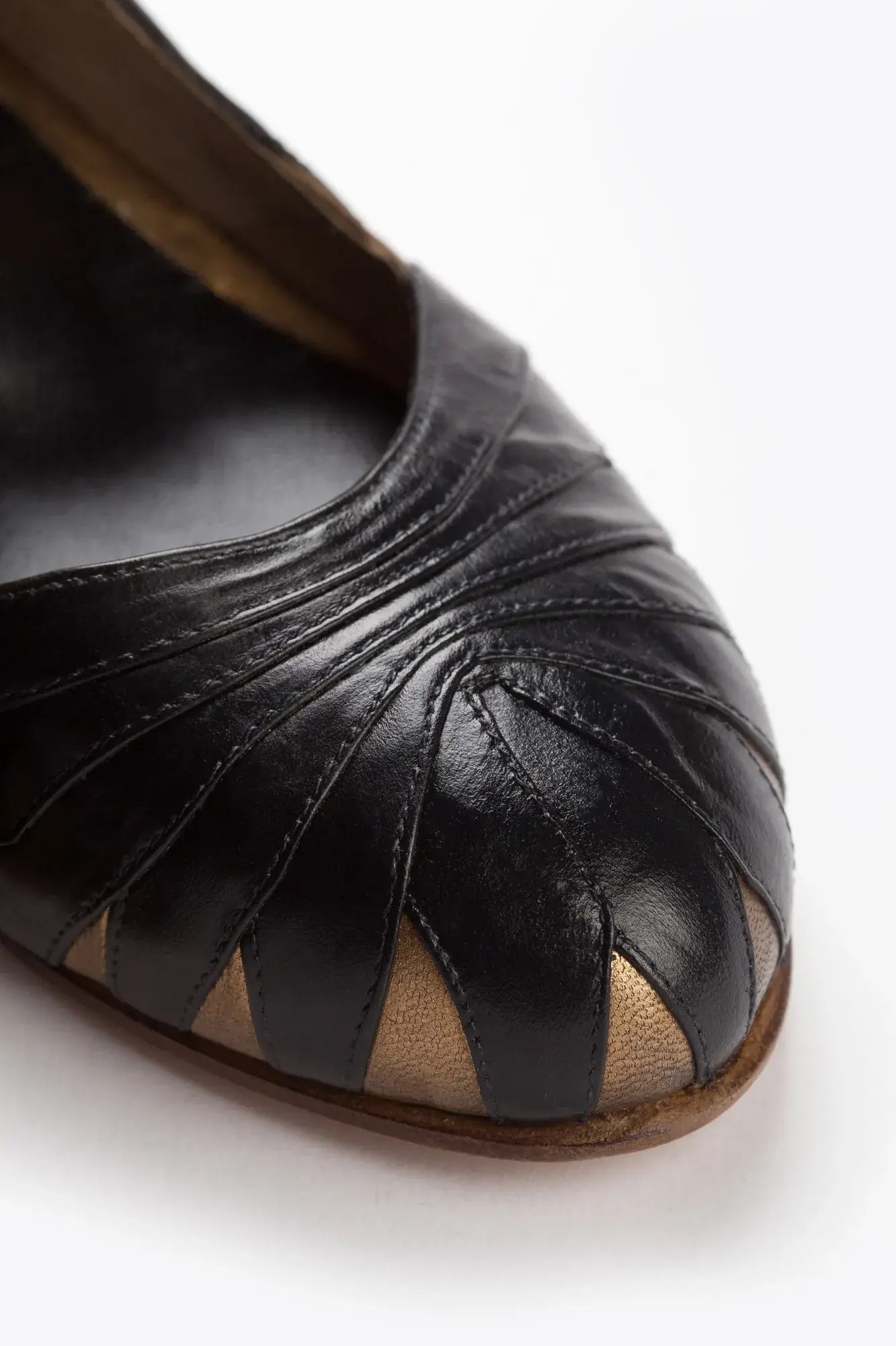 Cutout toe detail of a black and gold Mary Jane