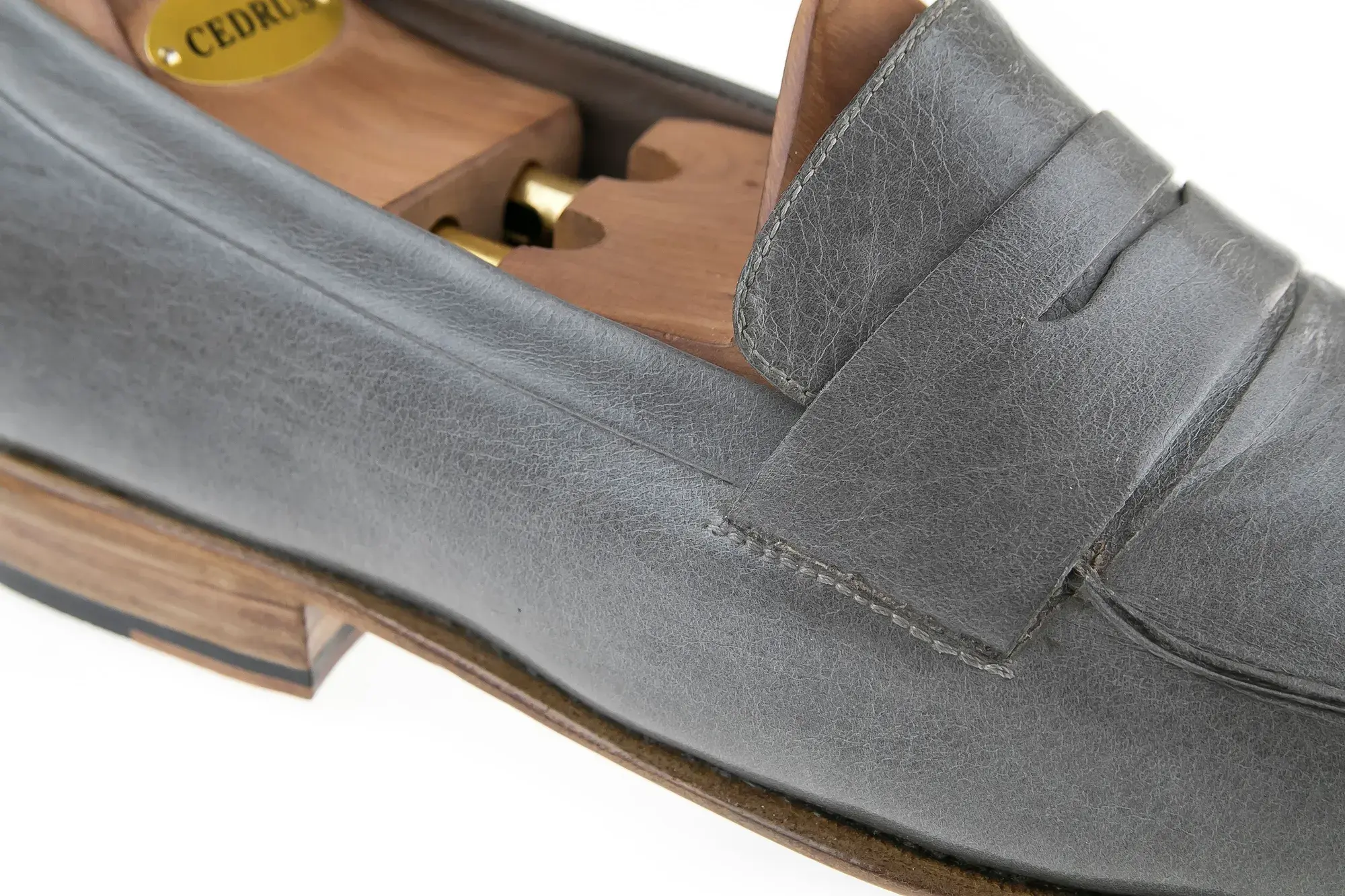 Saddle detail of a grey penny loafer