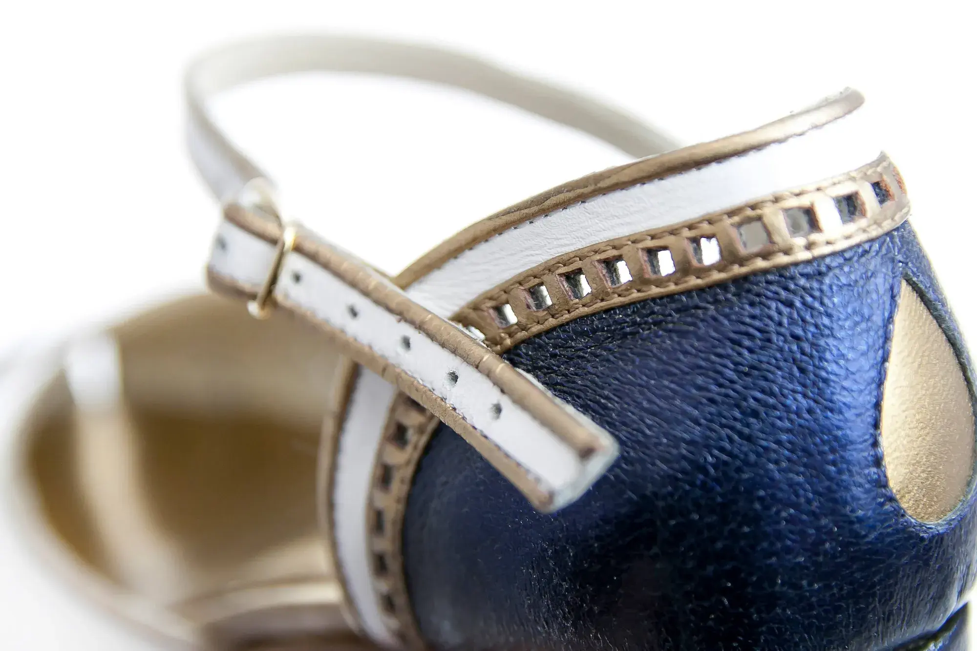 Strap detail of a navy, white and gold Mary Jane