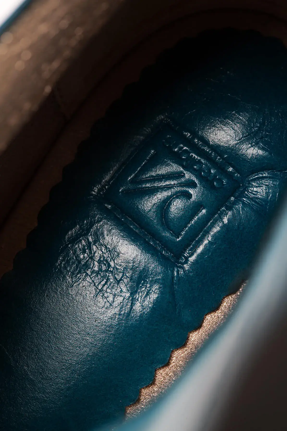The insole of a teal lace-up, stamped with the maker's mark