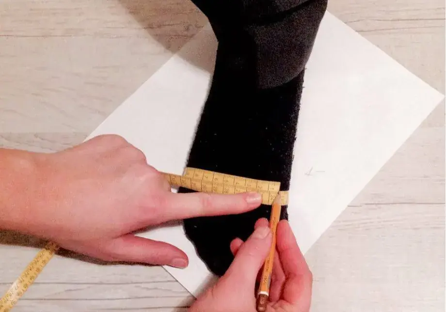 A tape measure around the ball of the foot, with the figure being written down