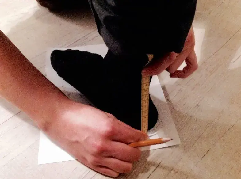 A tape measure held upright against the back of the heel