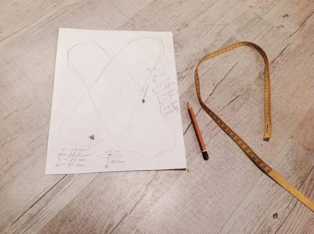 A finished tracing of both feet with measurements written beside it, a pencil and a tape measure