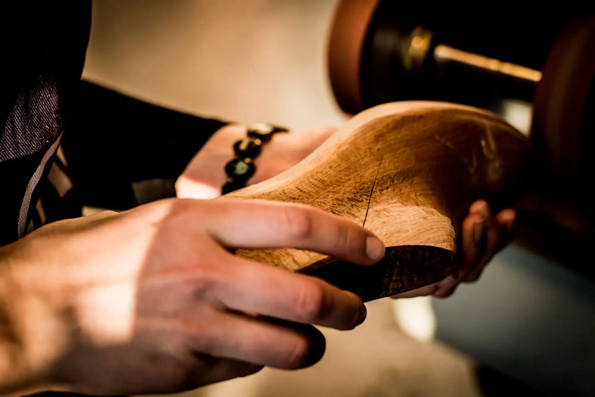 Hands turning a wooden last to check its shape