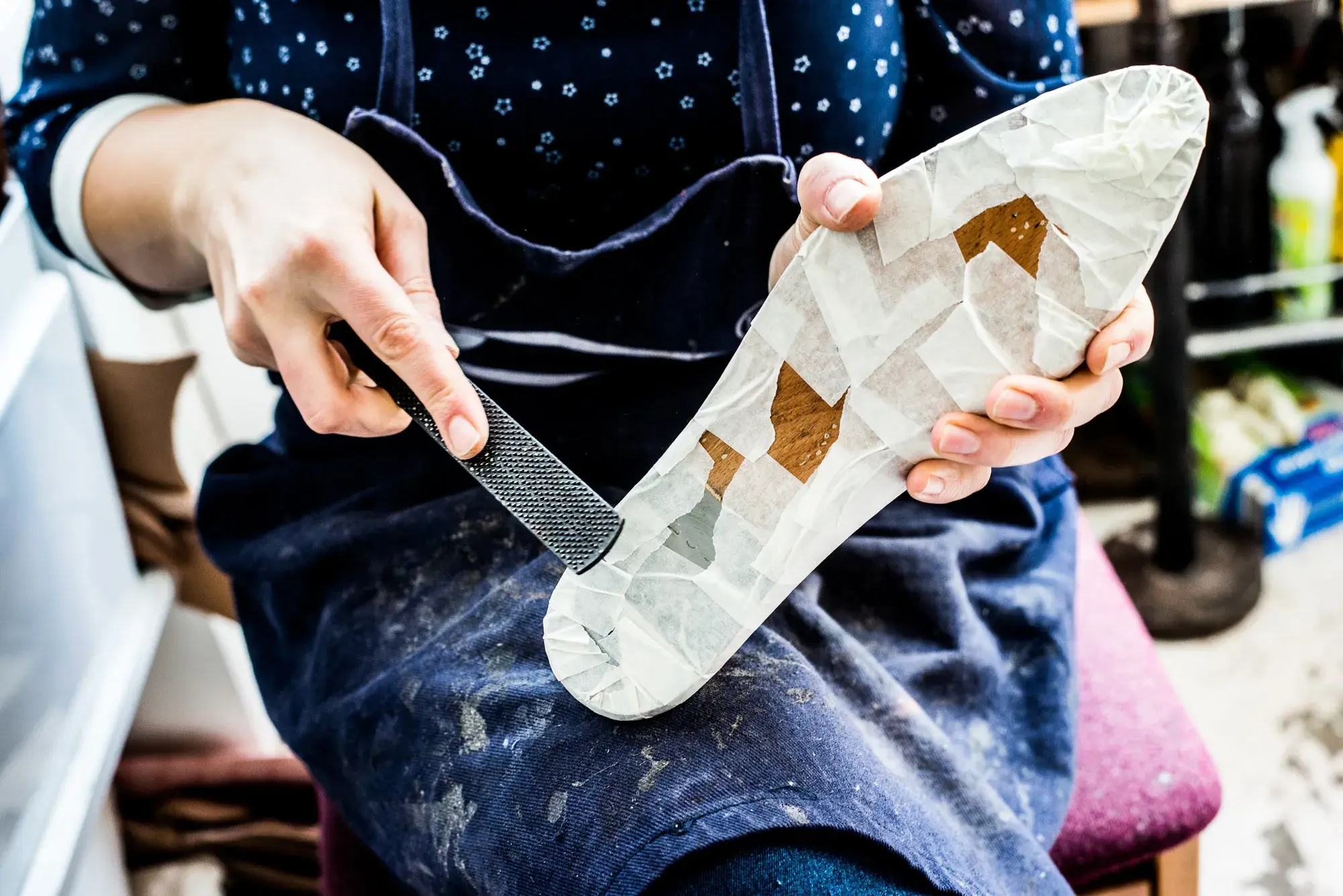 The taped last held sole-up while the tape is trimmed at the bottom