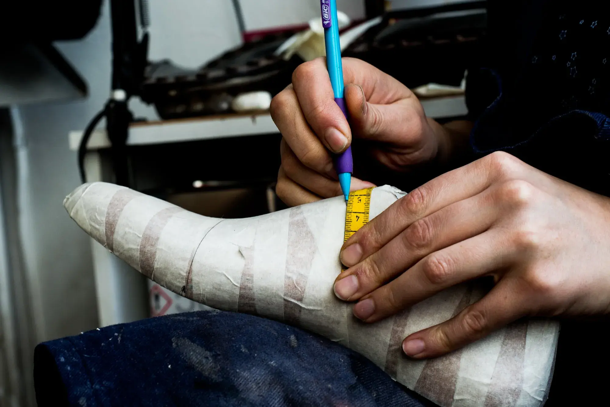 A blue pen marking a point on the taped last beside a tape measure