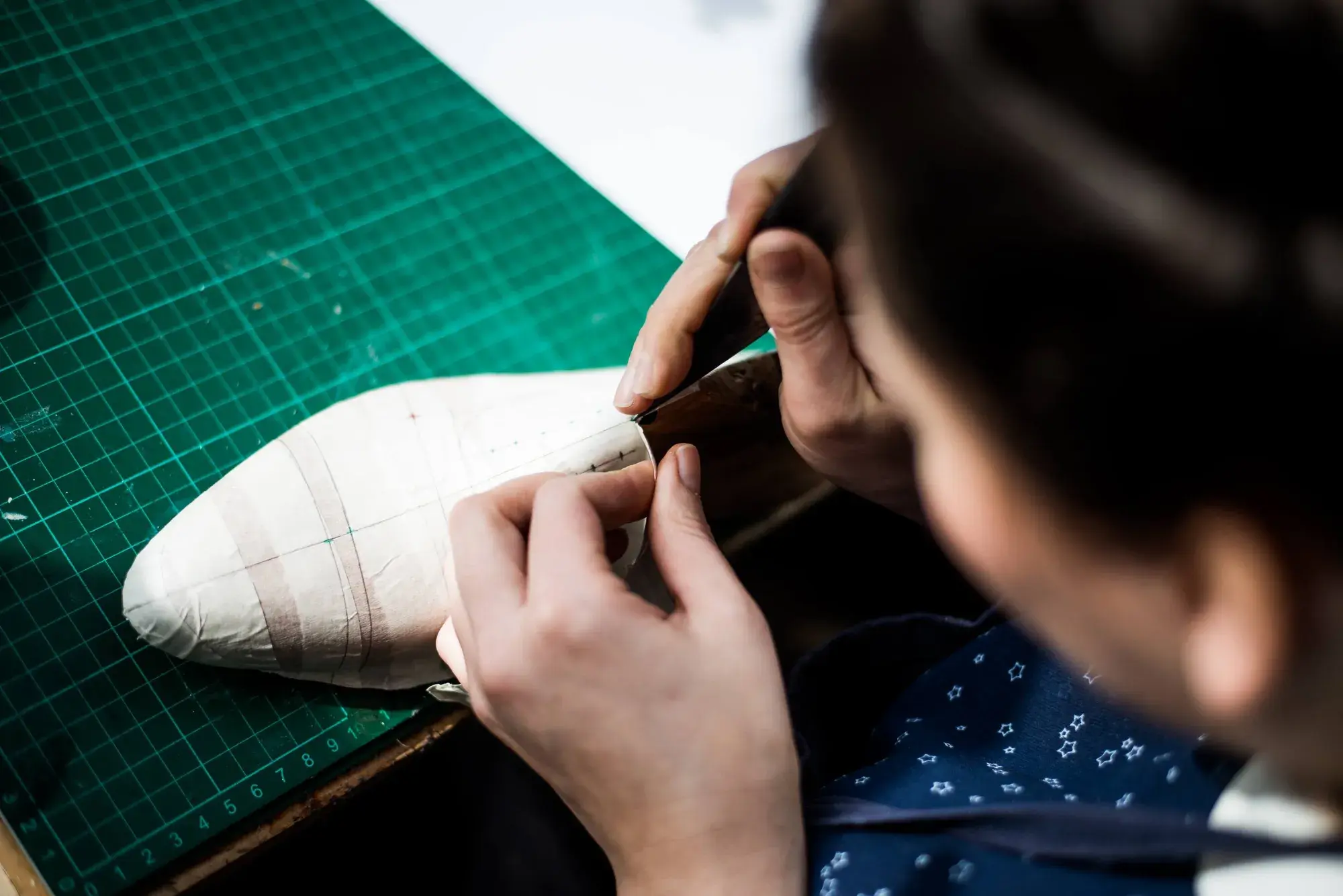 A knife trimming the taped shell along a drawn line on the last