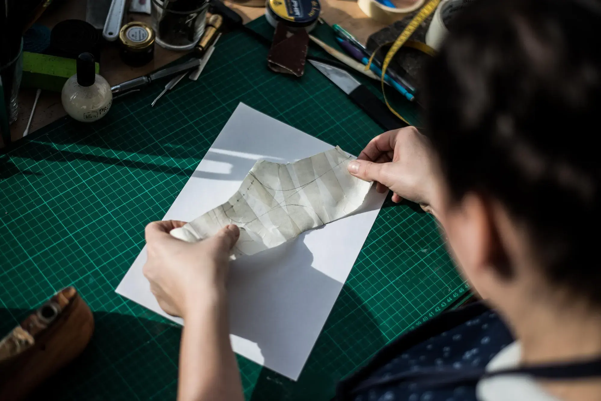 Hands laying the curled tape shell onto white paper