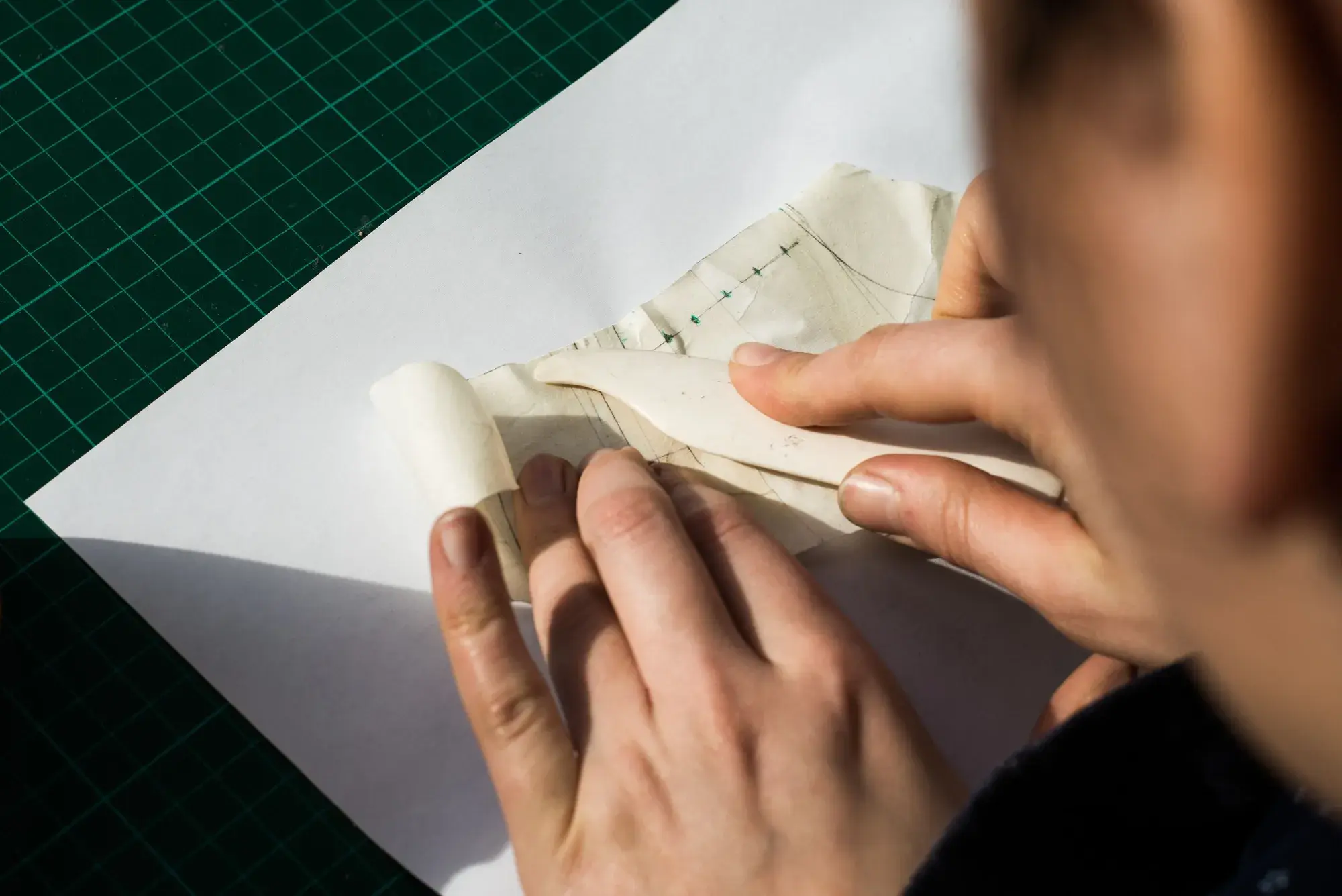 A bone folder pressing the tape shell flat on paper