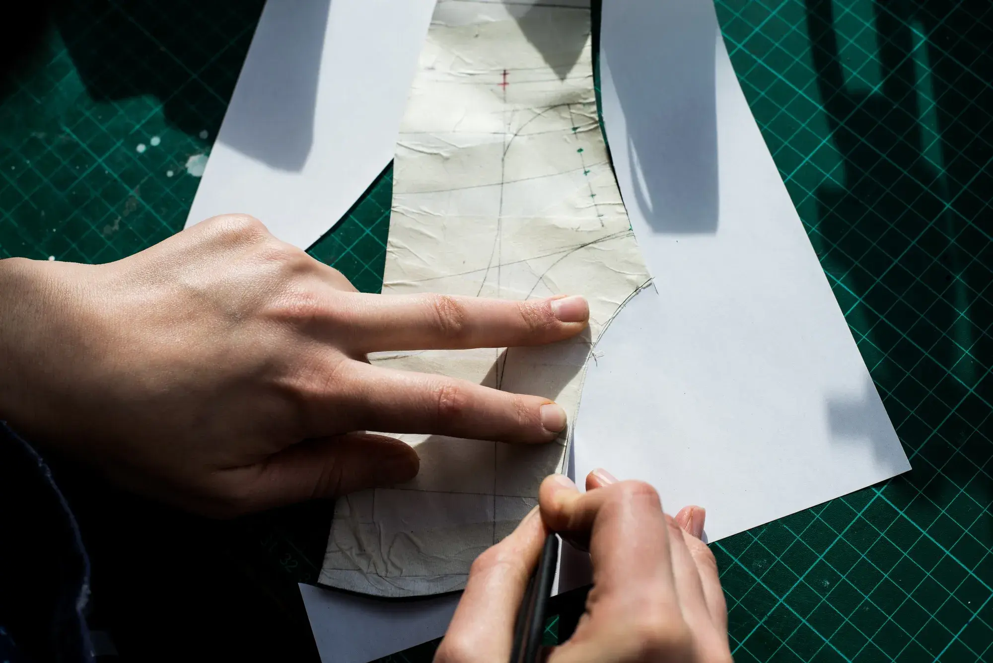 Fingers holding the flattened shell while its edge is traced