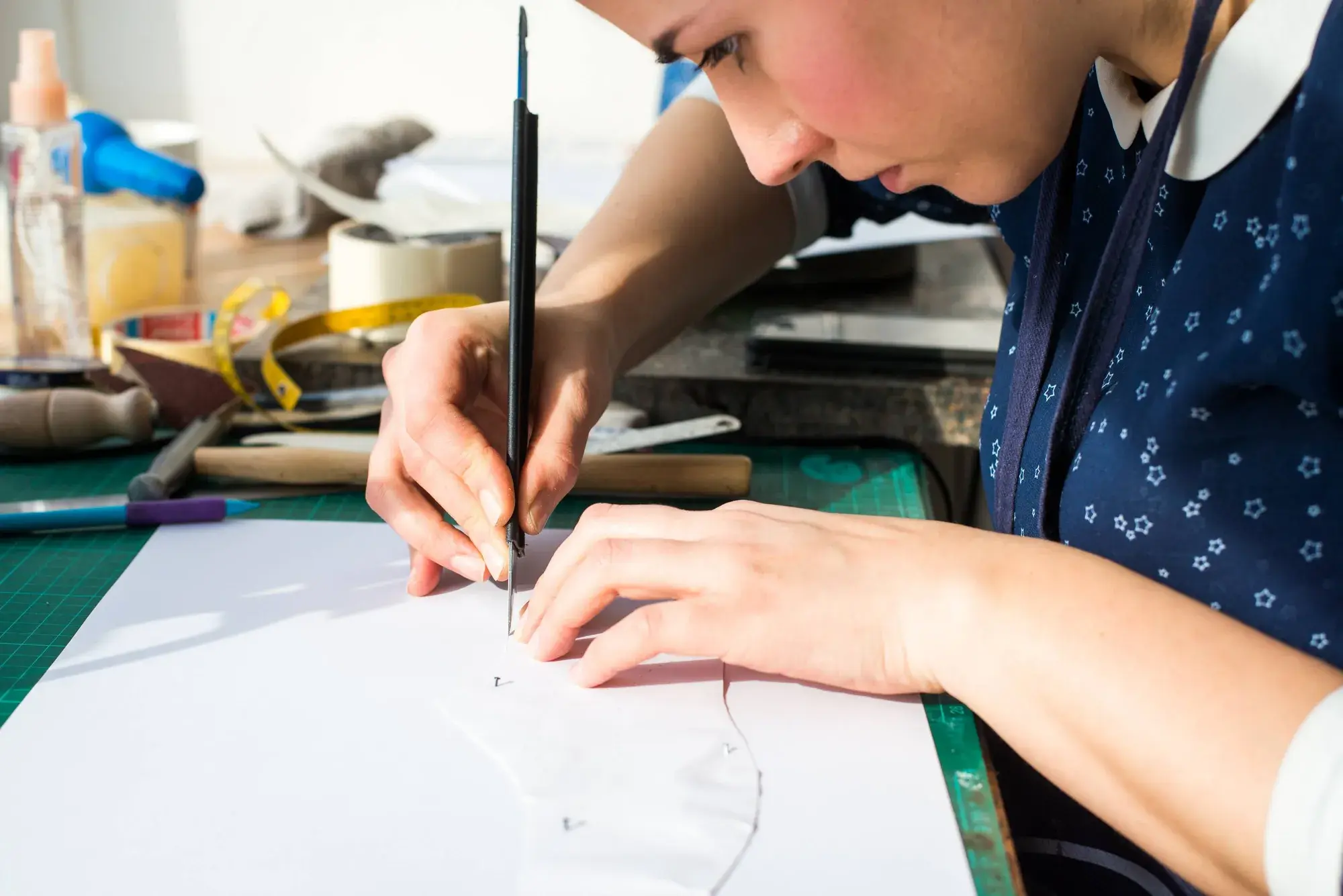 The maker leaning over the bench, drawing the pattern