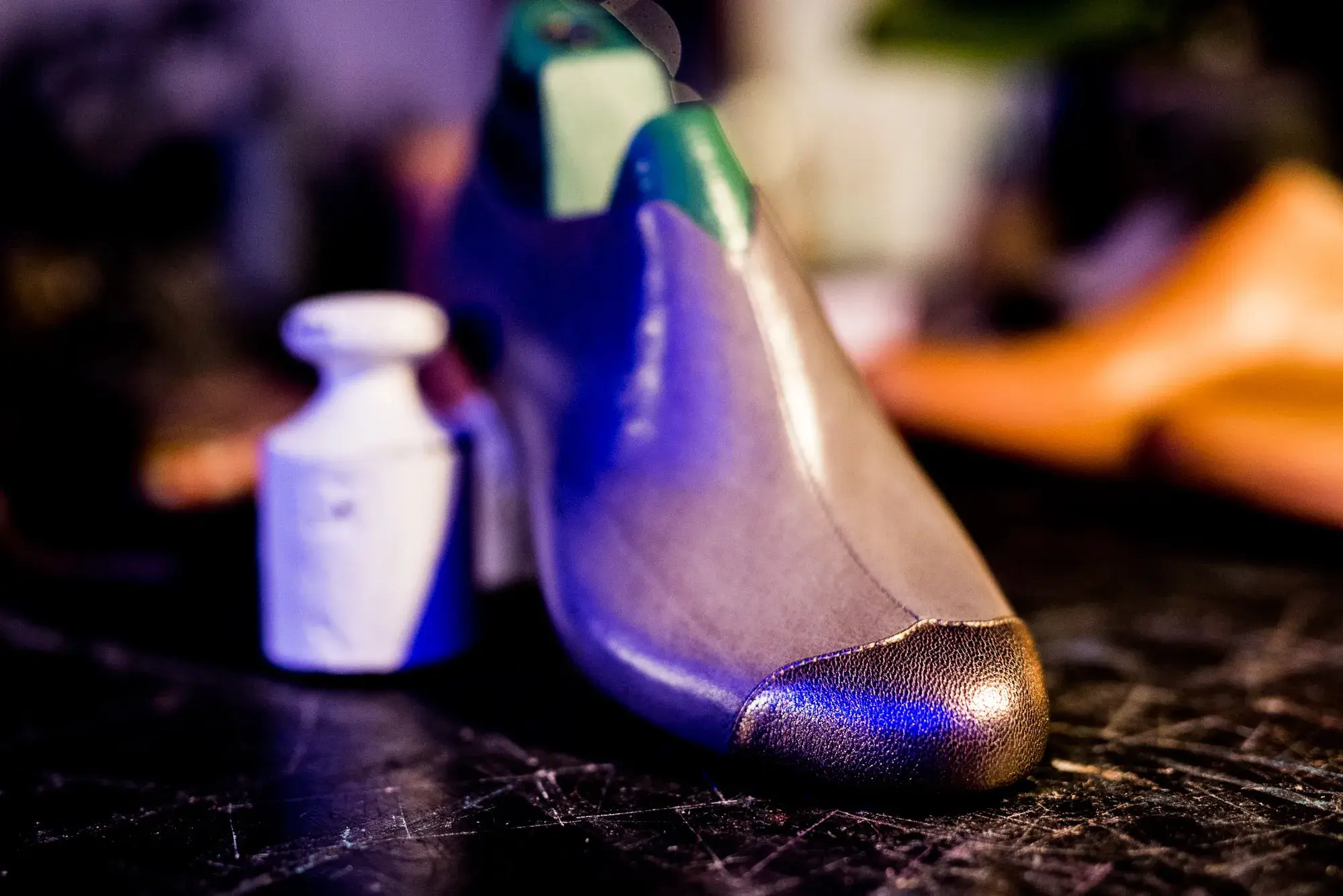 A purple trial shoe with a gold toe on the bench