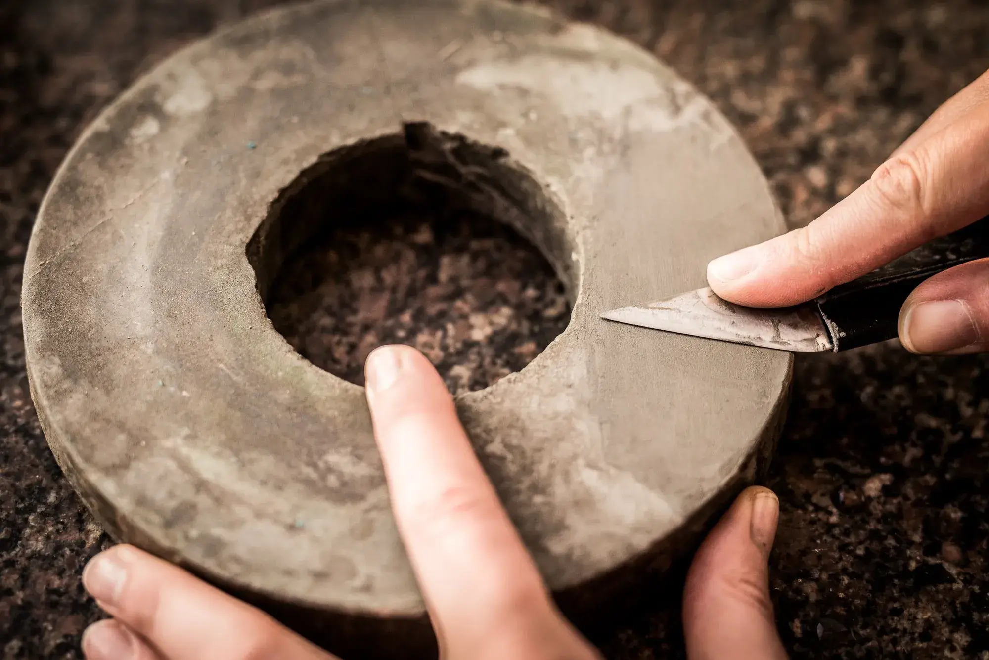 A knife being sharpened on a round whetstone