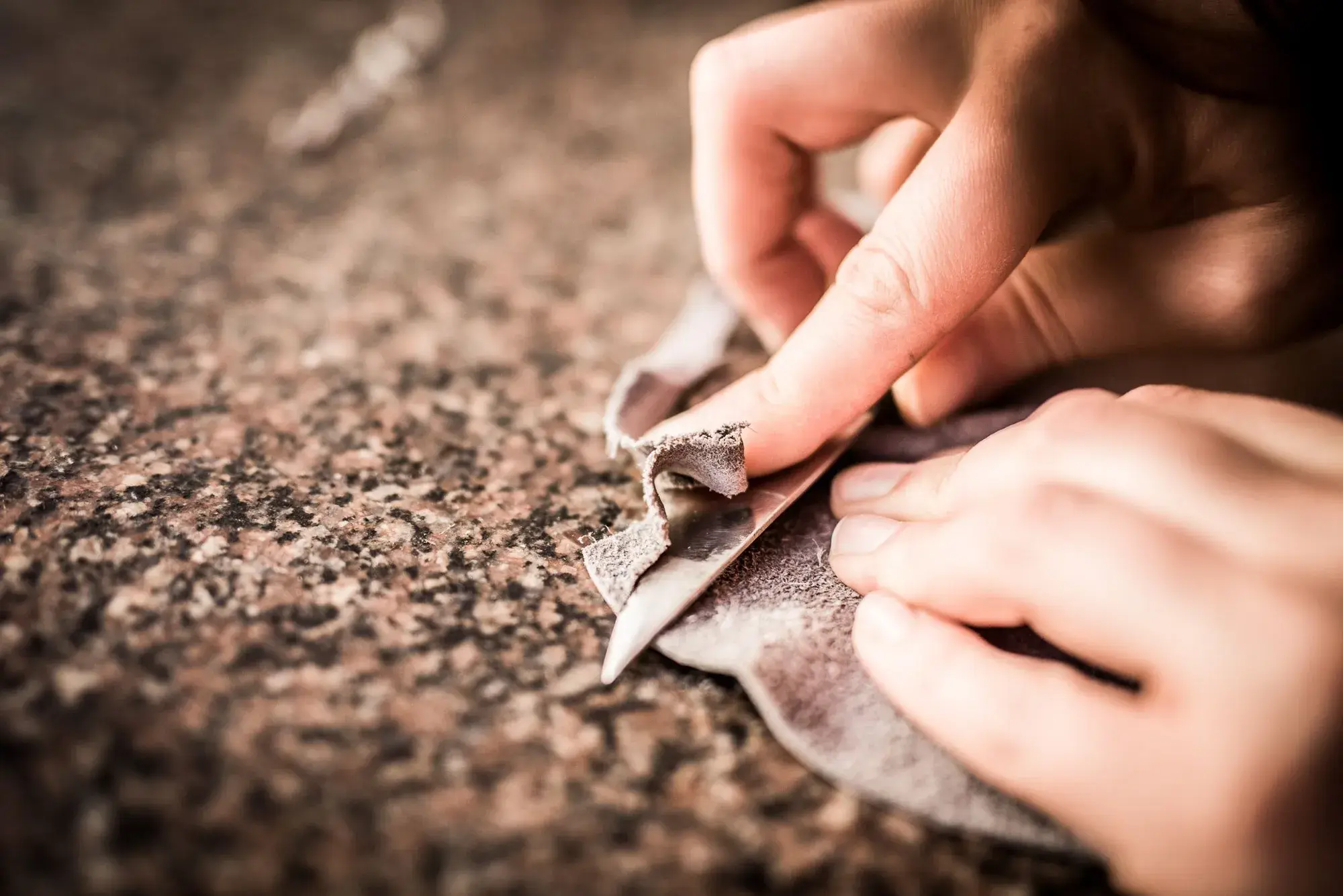 A knife thinning the edge of a leather piece