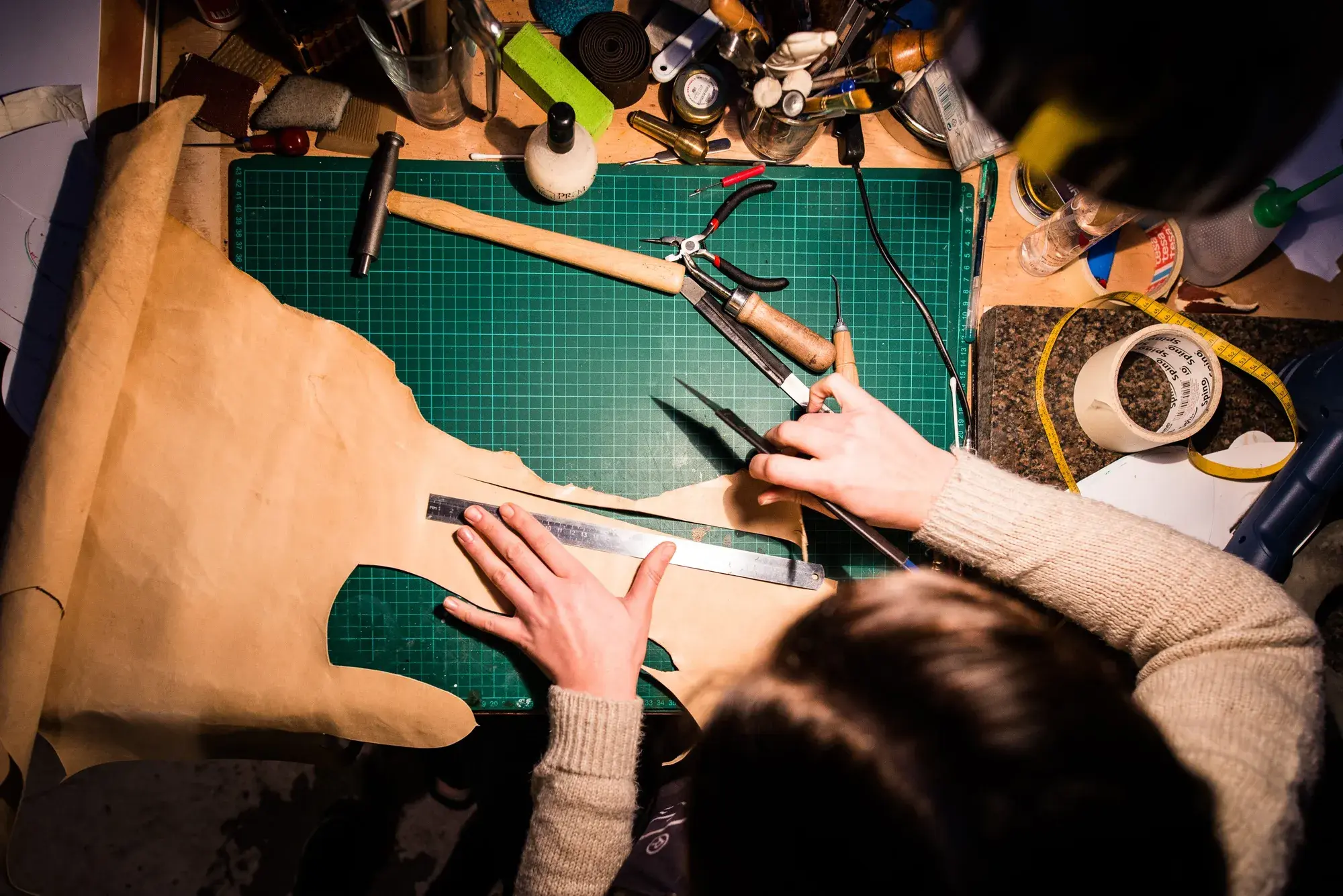 Overhead view of sole leather being cut on the green mat