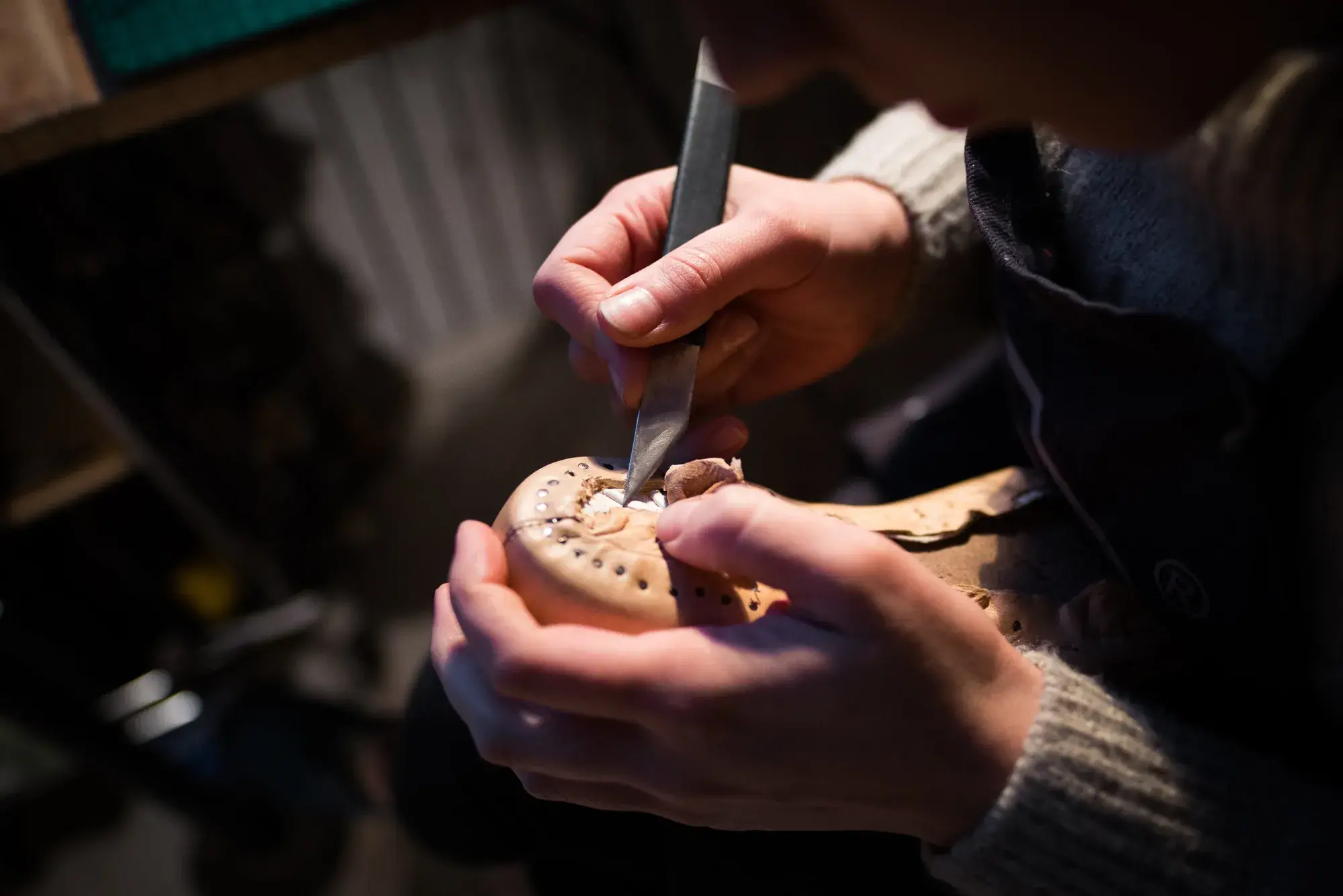 Hands carving a leather insole with a knife