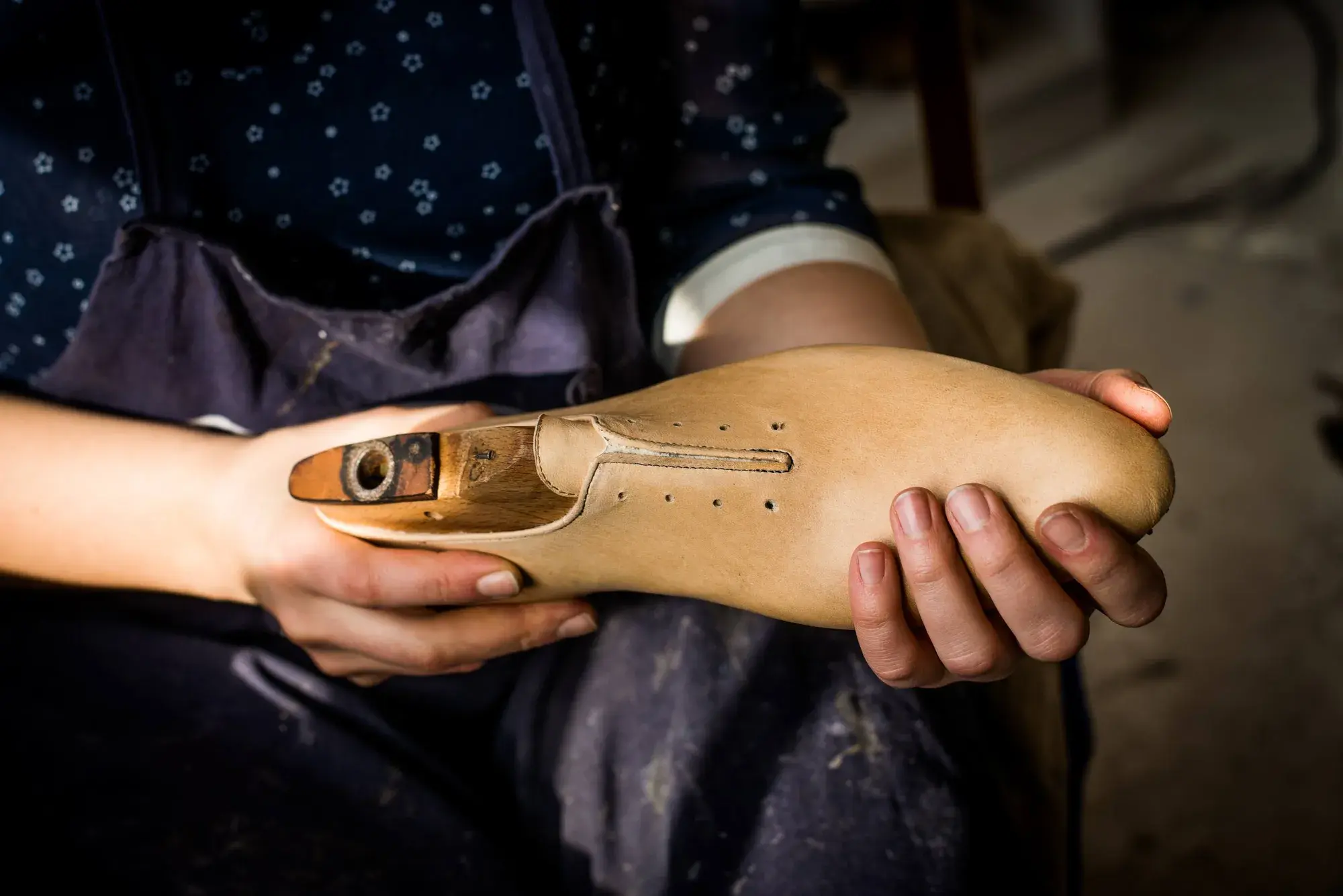 Hands holding a leather insole next to the last