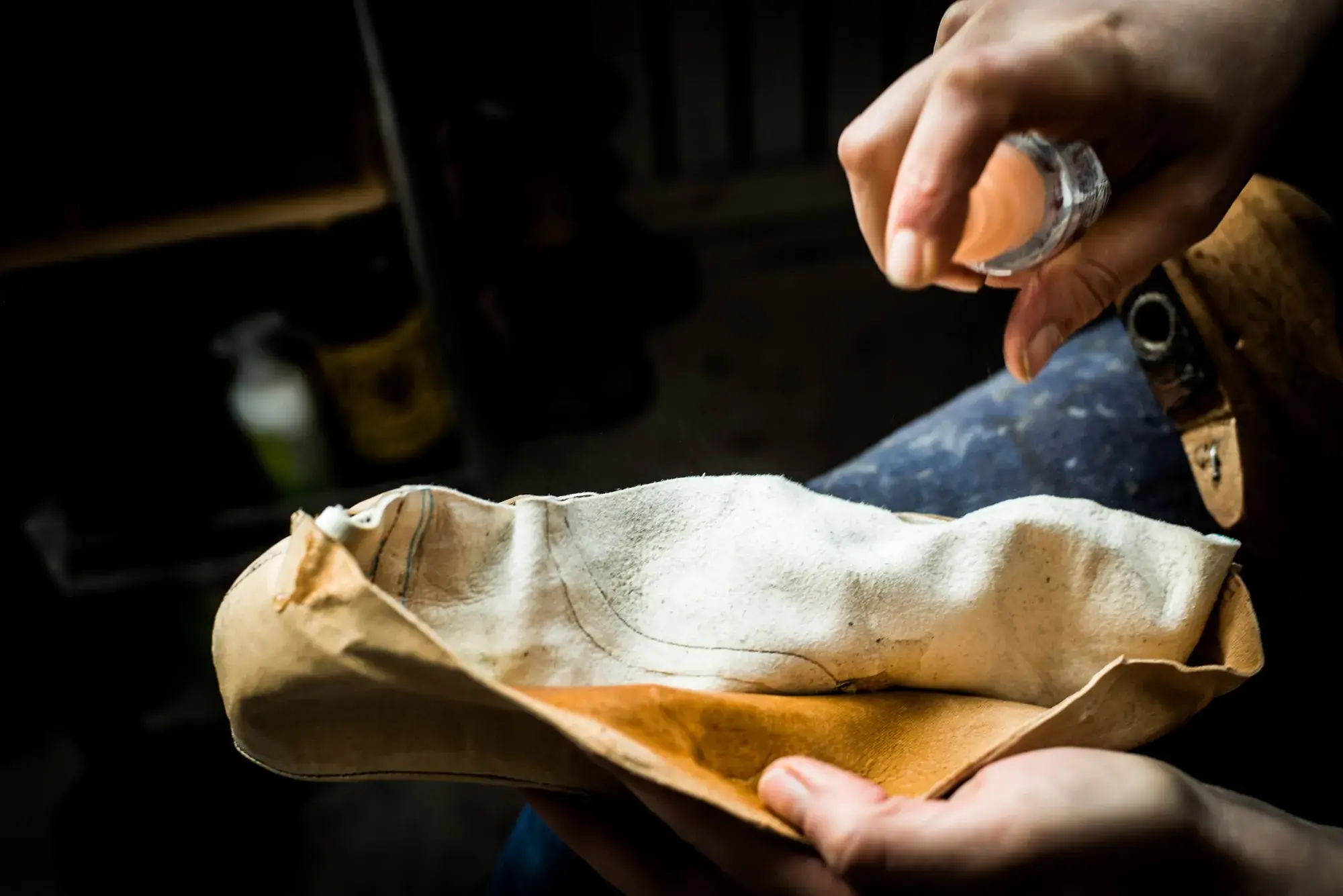 A sponge dabbing water onto a leather upper