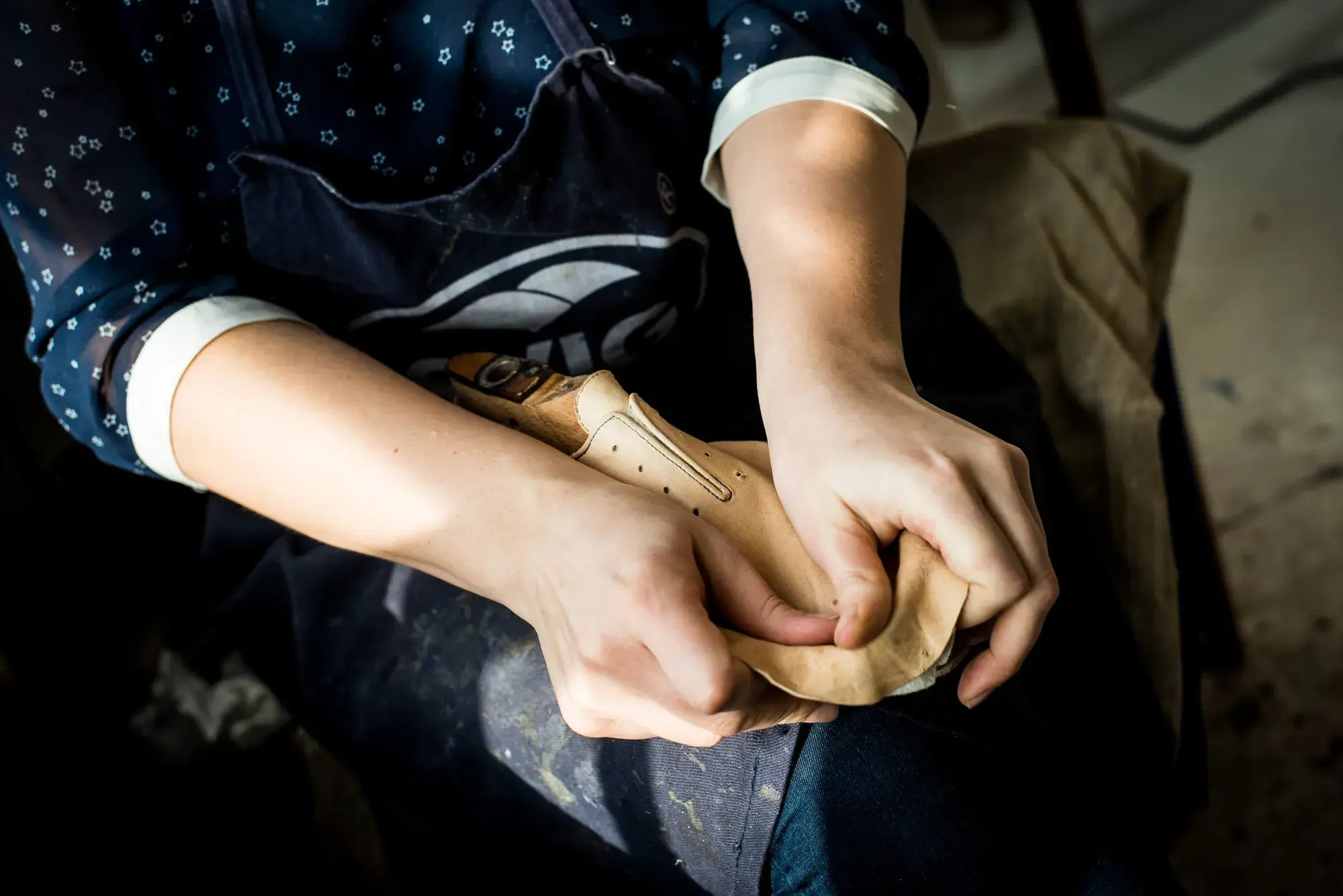 Hands moulding damp leather over the last