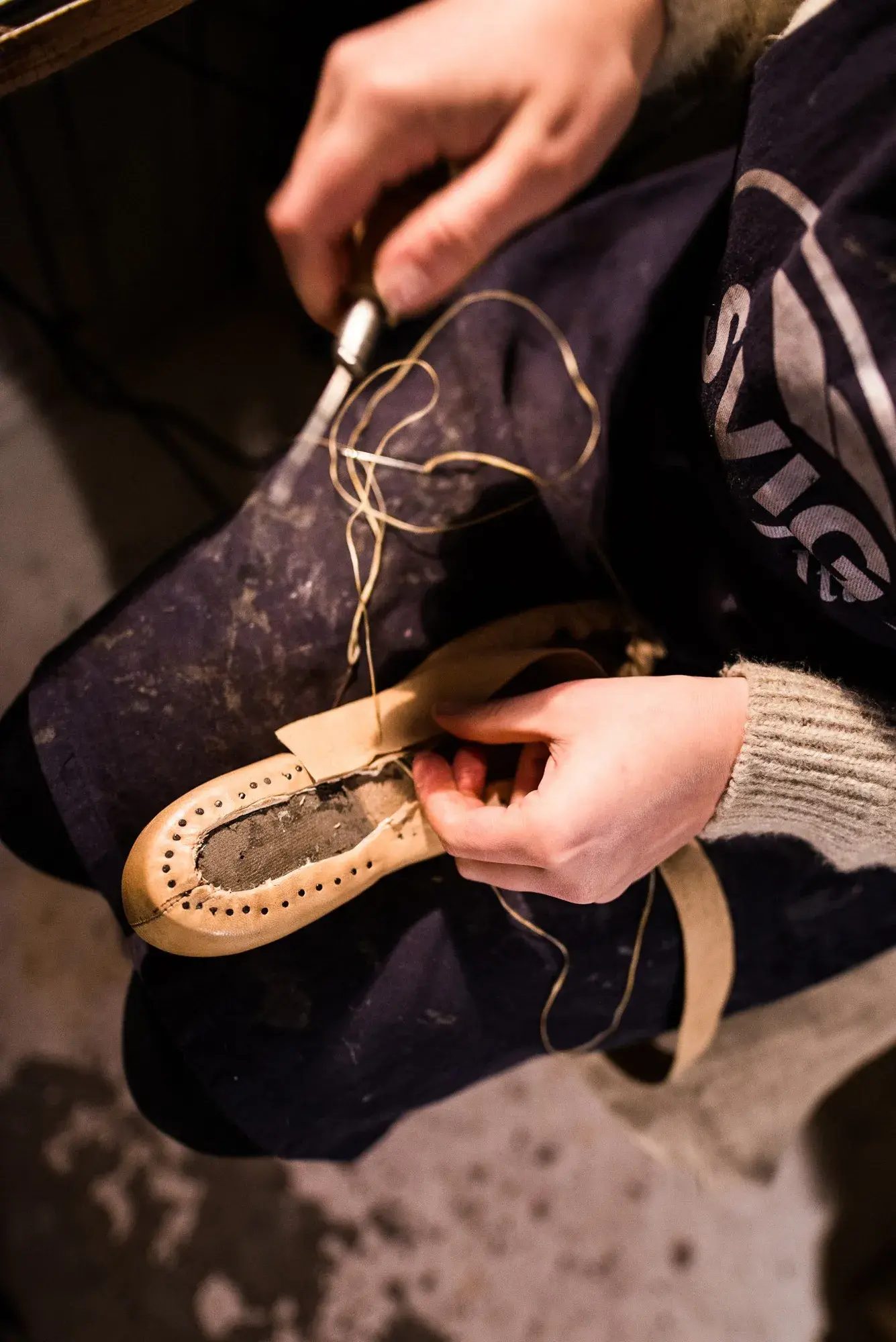 Hands stitching the welt with thread