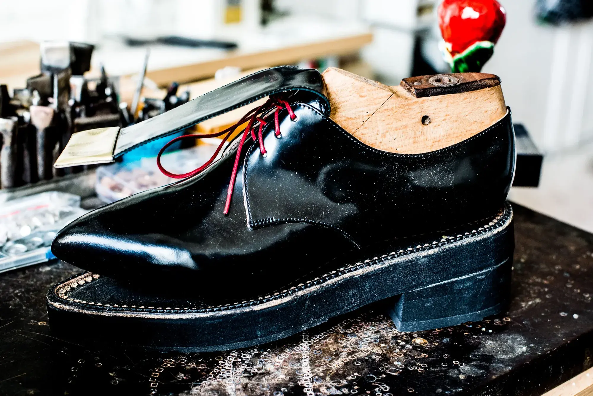 A black patent shoe on its last on the bench