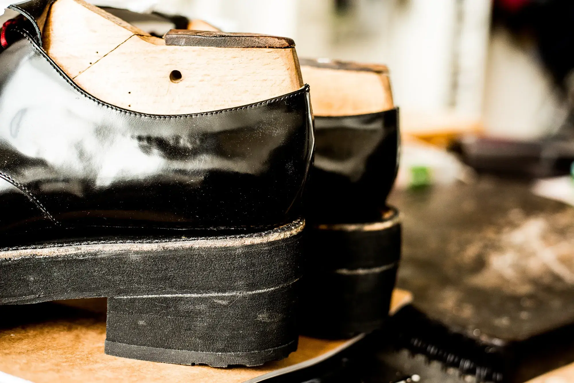 The heels of a pair of black patent shoes, seen from behind