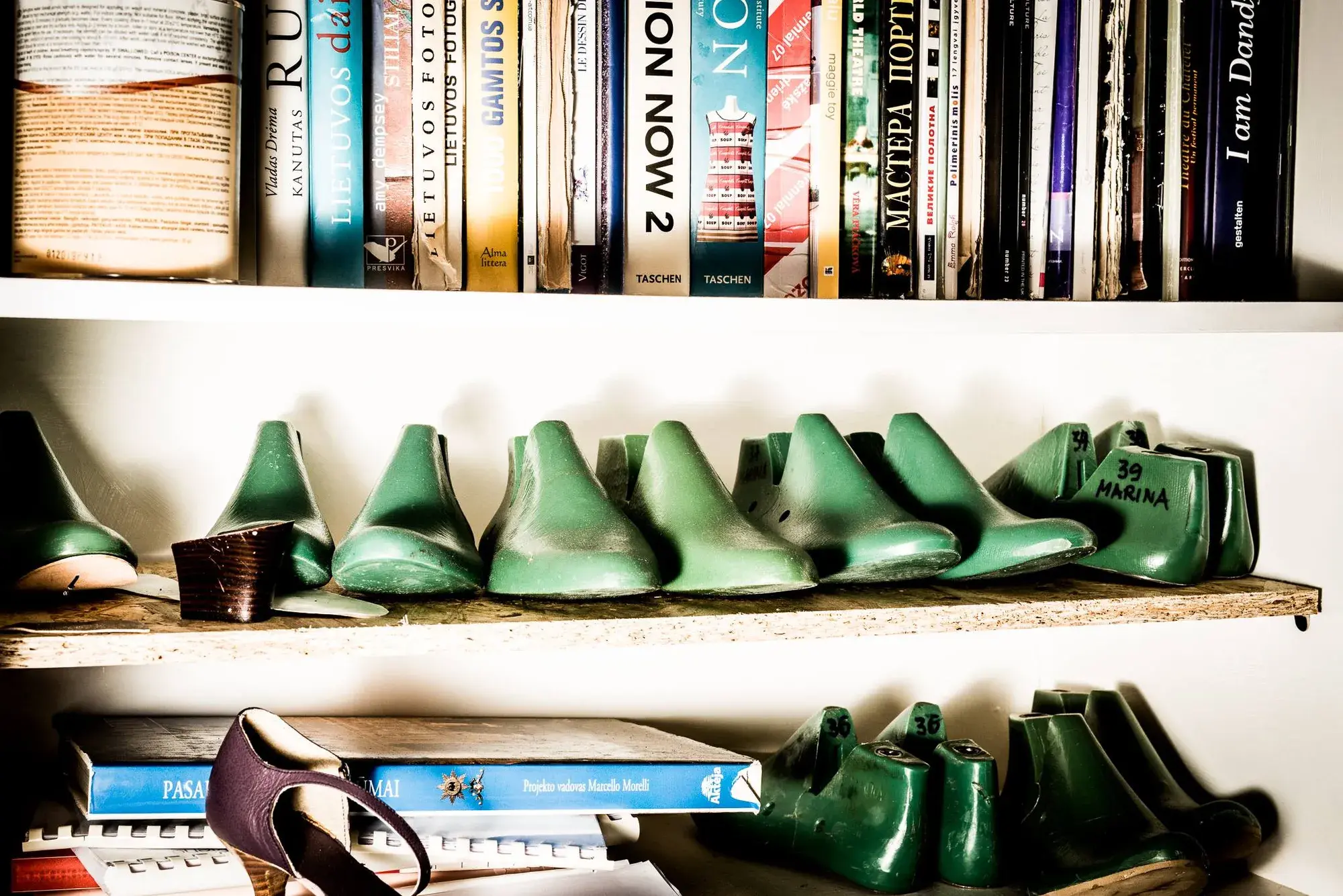 Green lasts lined up on a bookshelf between rows of books
