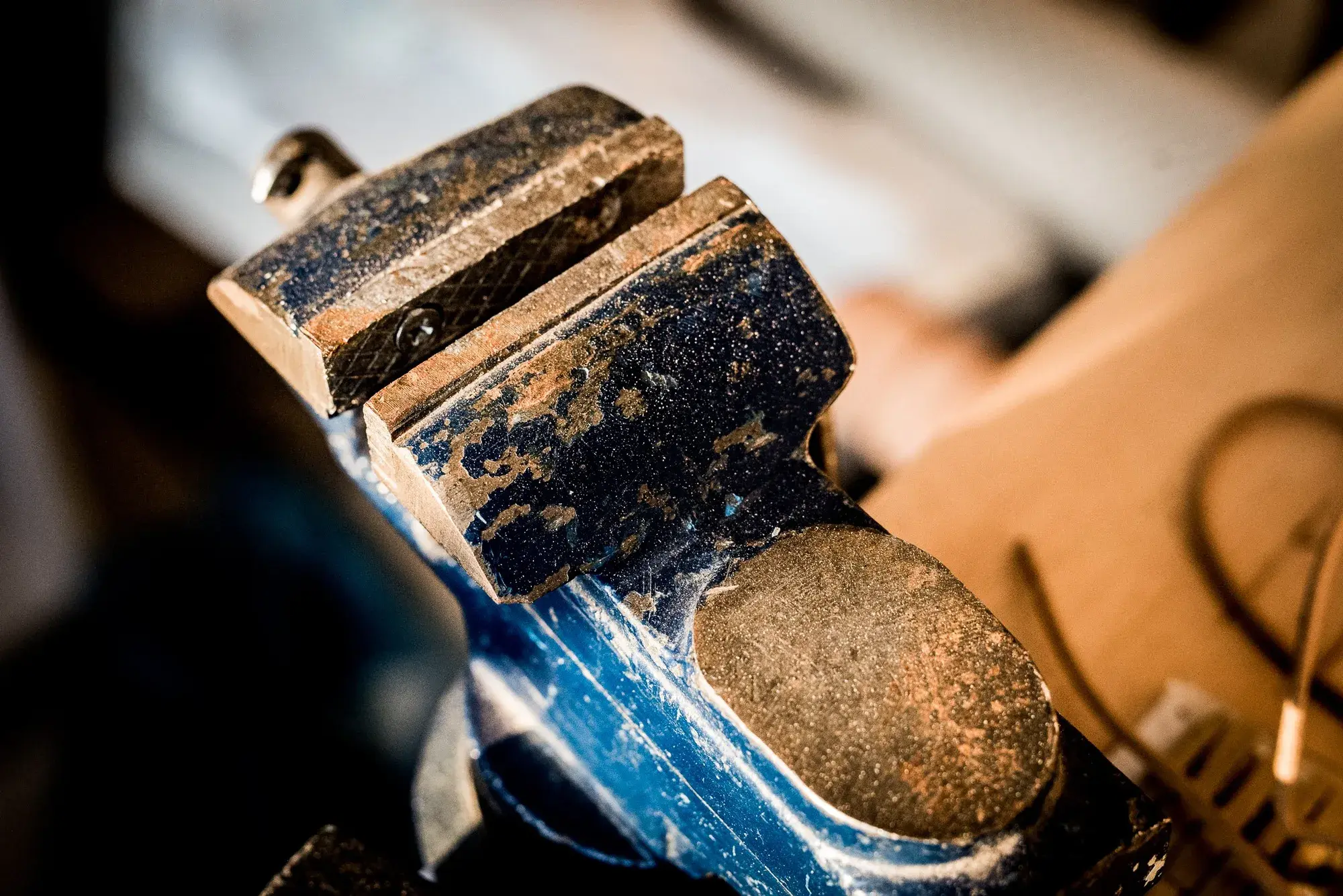 A last held in the jaws of a worn blue bench vice