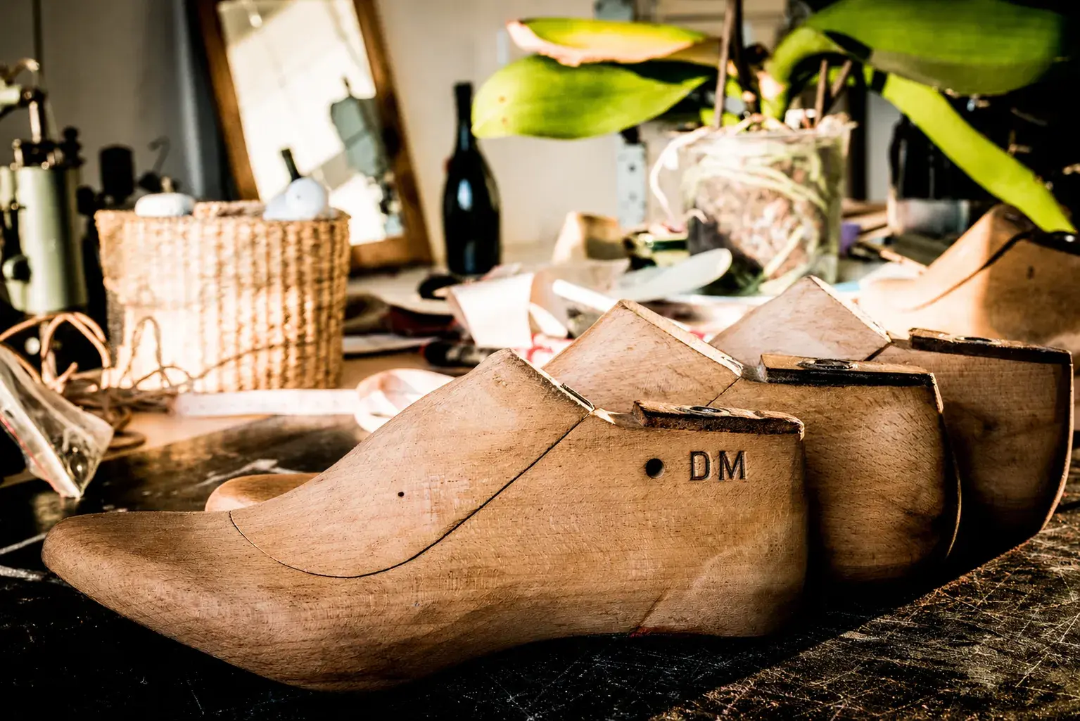 Wooden lasts lined up on the workshop bench, the nearest stamped DM